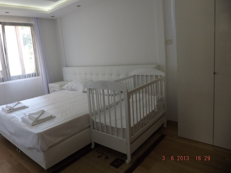Bright bedroom with a double bed and a baby cradle in an apartment in Pržno, Montenegro, with a modern interior.