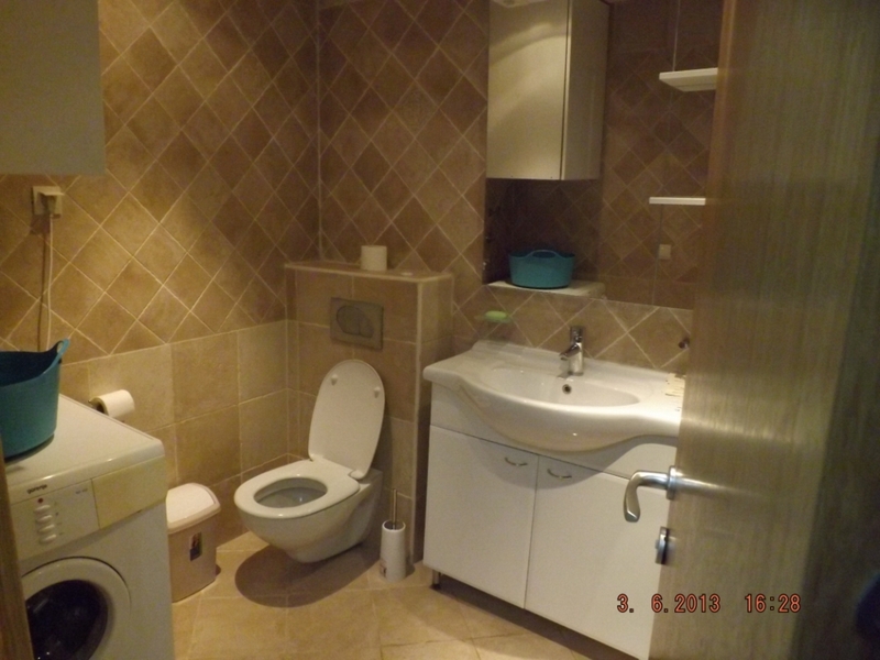 Bathroom in an apartment in Pržno, Montenegro: white fixtures, vanity under the sink, and beige-toned tiles.