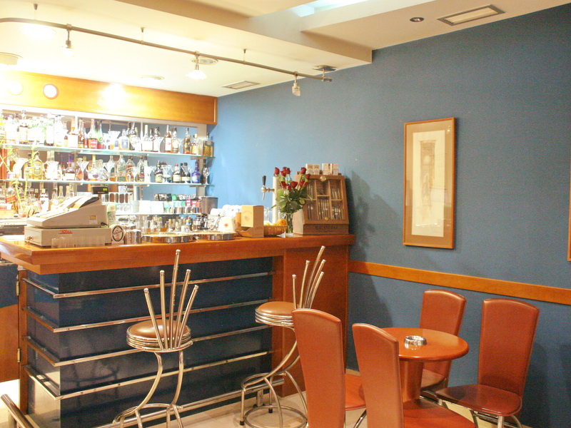 Bar interior in a hotel in Tivat, Montenegro: wooden bar counter, high stools, and tables with leather armchairs.
