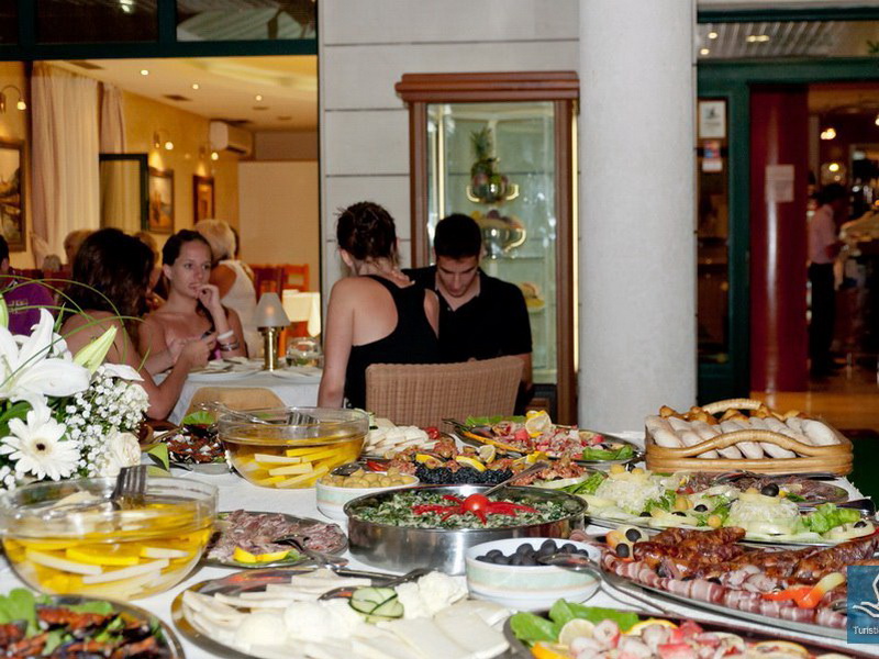 Buffet with appetizers in the hotel restaurant in Tivat, Montenegro: dishes served and guests in the dining room.