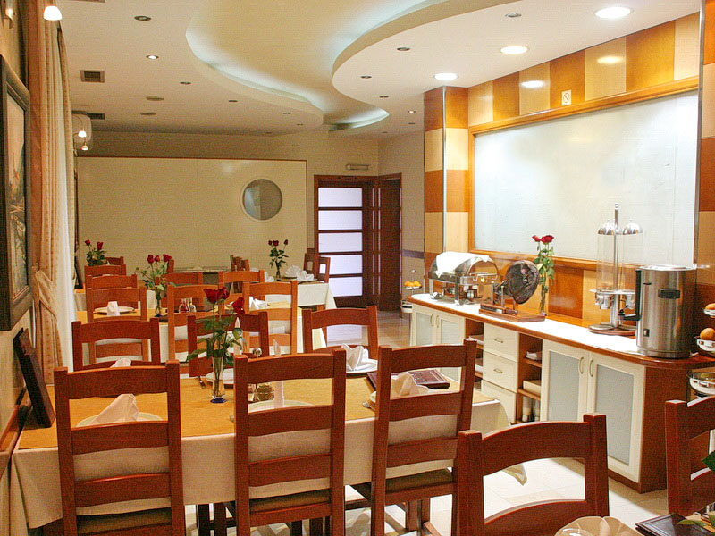 Hotel dining room interior in Tivat, Montenegro: wooden furniture, set tables, and a buffet area.