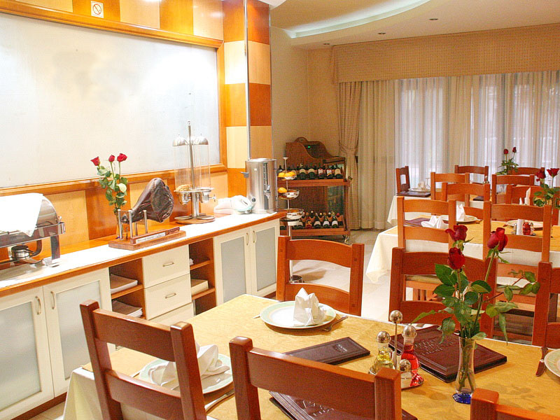 Hotel dining room interior in Tivat, Montenegro: wooden tables, table settings, buffet area, and decor.
