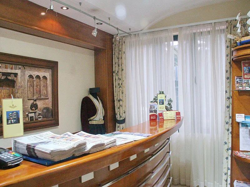 Reception desk with wooden counter, newspapers, payment terminal, and a traditional costume on a mannequin.
