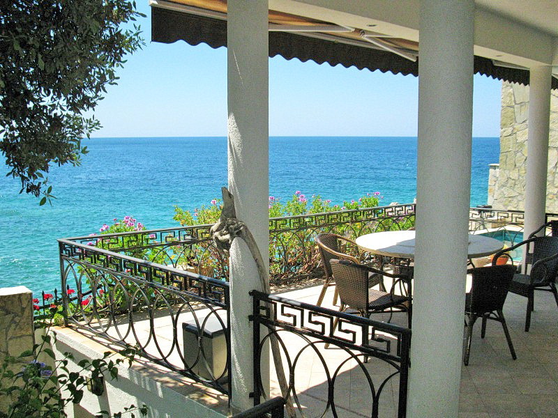 Villa terrace in Dobra Voda, Montenegro: sea view, wrought-iron railings, wicker furniture, and stone finishes.