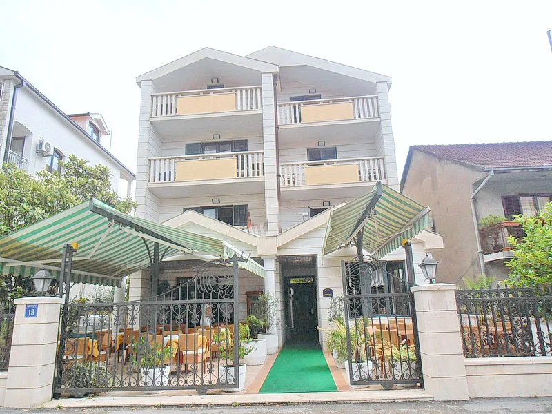 Exterior view of a multi-story building facade with balconies and a shaded patio area.
