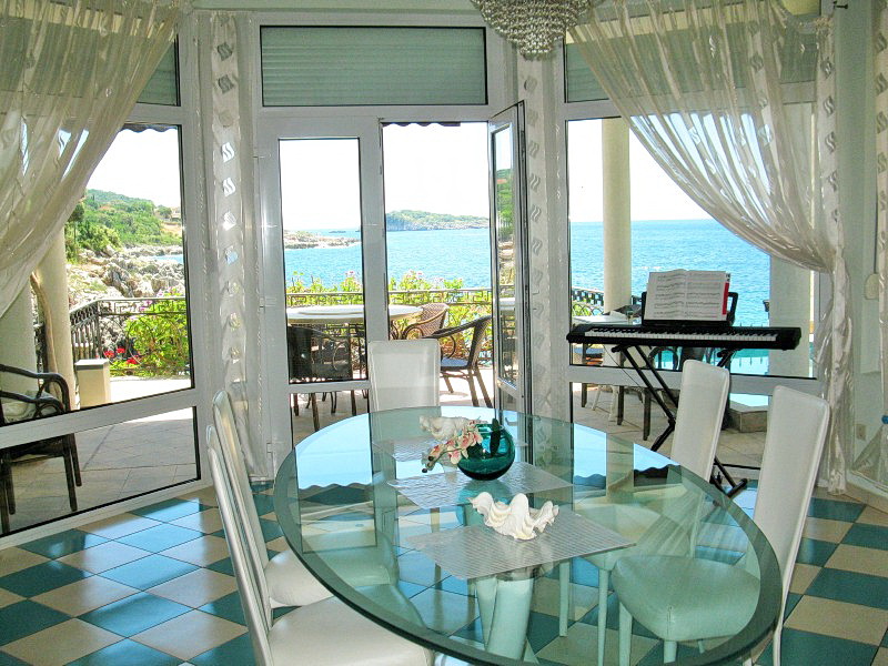 Living room with panoramic sea view and a terrace in a villa in Dobra Voda, Montenegro: glass table and synthesizer.