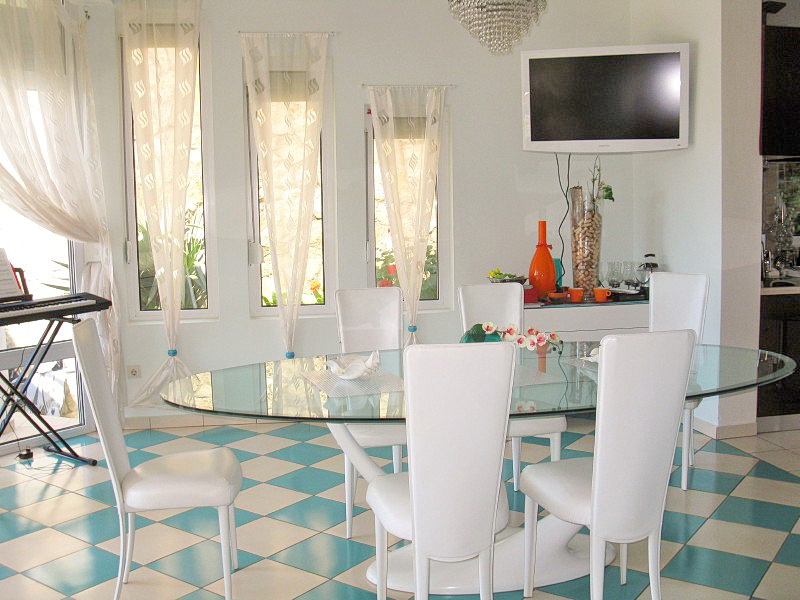 Bright living room with a dining area and a glass table in a villa in Dobra Voda, Montenegro. Interior with checkered tile flooring.