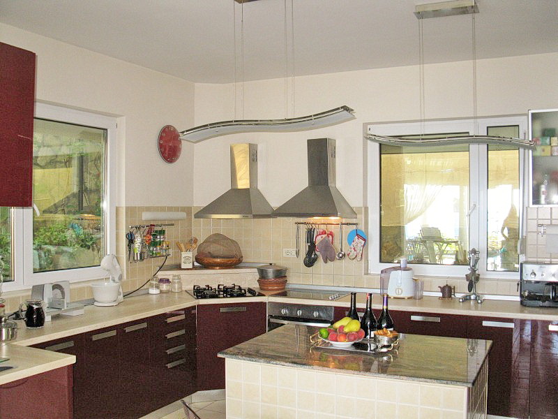 Modern kitchen with an island and appliances in a villa in Dobra Voda, Montenegro: burgundy fronts and a stone countertop.