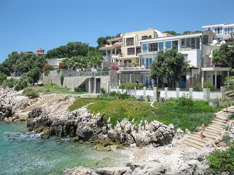 Villa on the seafront in Dobra Voda, Montenegro: a modern building with terraces by the rocky shore and beach.