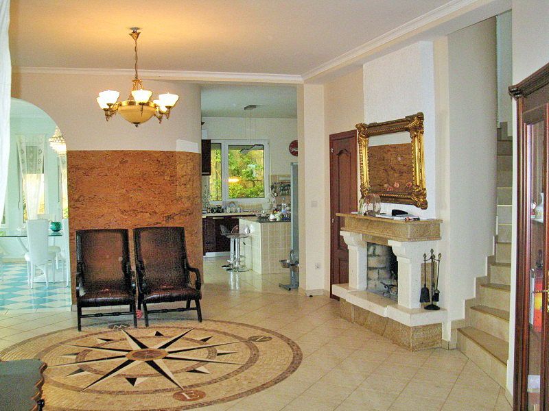 Living room with a fireplace and mosaic floor in a villa, Dobri Vody, Montenegro. Interior with a staircase and kitchen area.