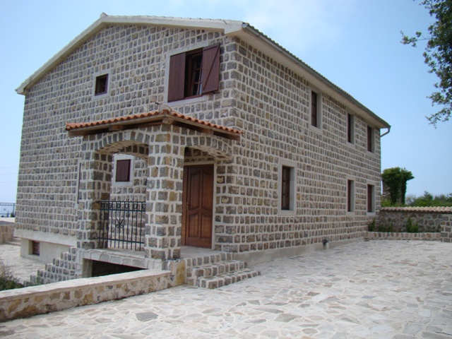 Two-story natural stone house with a terrace in Petrovac, Montenegro: exterior with a tiled roof.