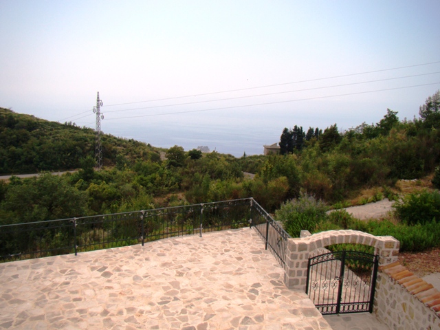 Terrace with stone flooring and wrought-iron railing, sea and mountain view in Petrovac, Montenegro.
