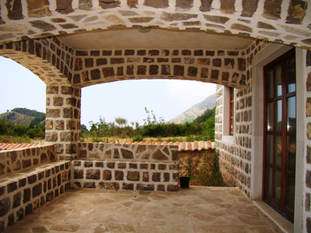 Covered stone terrace of a house in Petrovac, Montenegro, with mountain views and natural stone arches.