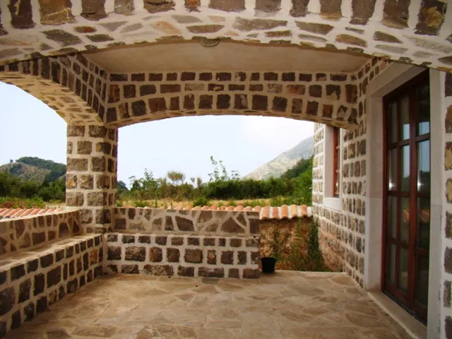 Stone arched terrace with mountain and vegetation view, featuring stone walls and floor.