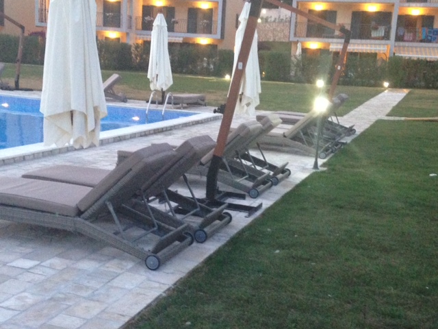 Outdoor pool with sun loungers and umbrellas at a residential complex in Budva, Montenegro, overlooking the landscaped grounds.