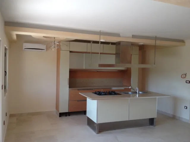 Modern kitchen featuring a central island with a cooktop, sink, and suspended cabinetry.