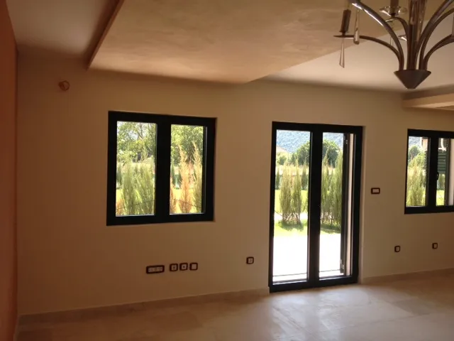 Empty room with windows and balcony door, chandelier, and electrical outlets on walls.