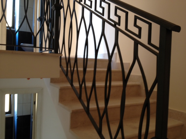 Staircase with wrought-iron railings and marble steps in an apartment, Budva, Montenegro. Modern home interior.