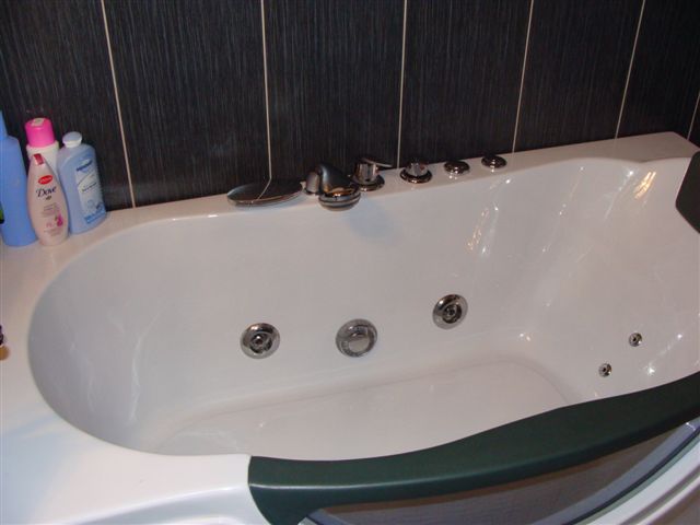 White whirlpool bathtub in a modern apartment bathroom in Budva, Montenegro, with dark wall finishes.