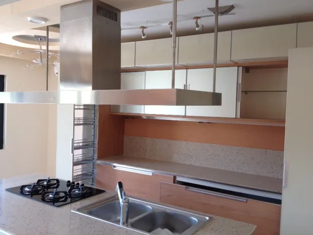 Kitchen with gas stove, stainless steel hood, and suspended cabinets, modern design.