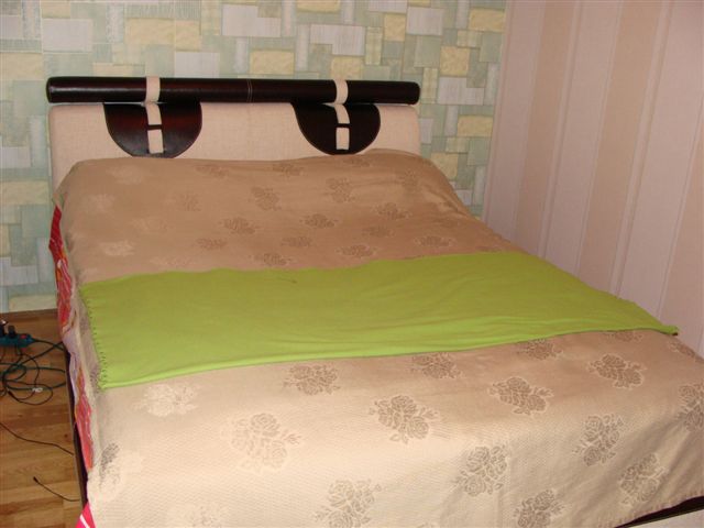 Double bed with a soft headboard in the bedroom interior of an apartment in Budva, Montenegro.