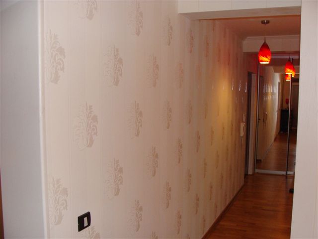 Bright hallway in an apartment in Budva, Montenegro: patterned wallpaper, wooden floor, and red ceiling lights.