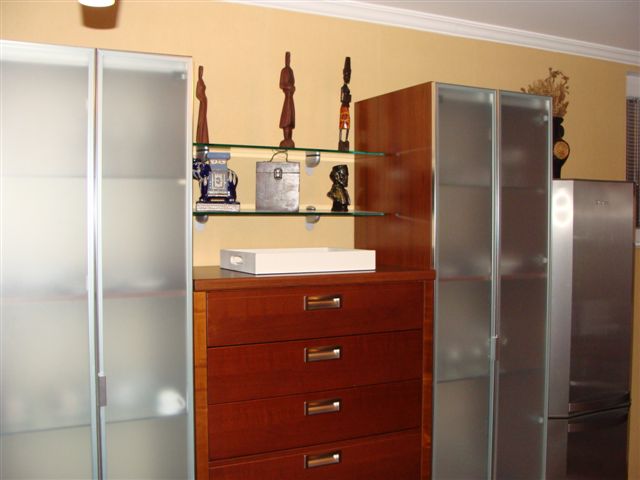 Living room interior in an apartment in Budva, Montenegro: a wooden dresser, glass display cabinets, and decor on the shelves.