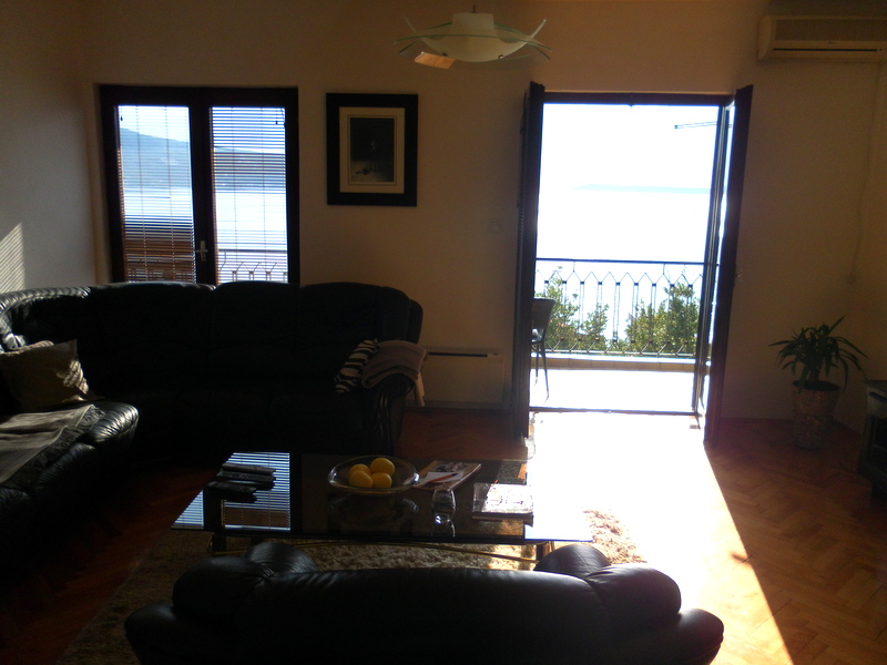 Living room in a house in Herceg Novi, Montenegro: leather sofa, glass table, and access to a balcony with panoramic sea views.