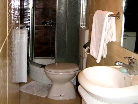 Bathroom in a house in Herceg Novi, Montenegro: shower cabin, plumbing fixtures, light-colored tiles, and a washing machine.