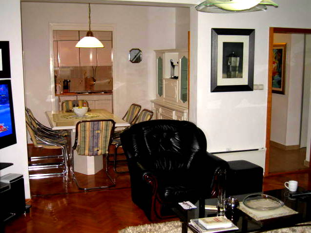 Living room with a black leather armchair and dining area in a house, Herceg Novi, Montenegro: interior with parquet flooring and furniture.