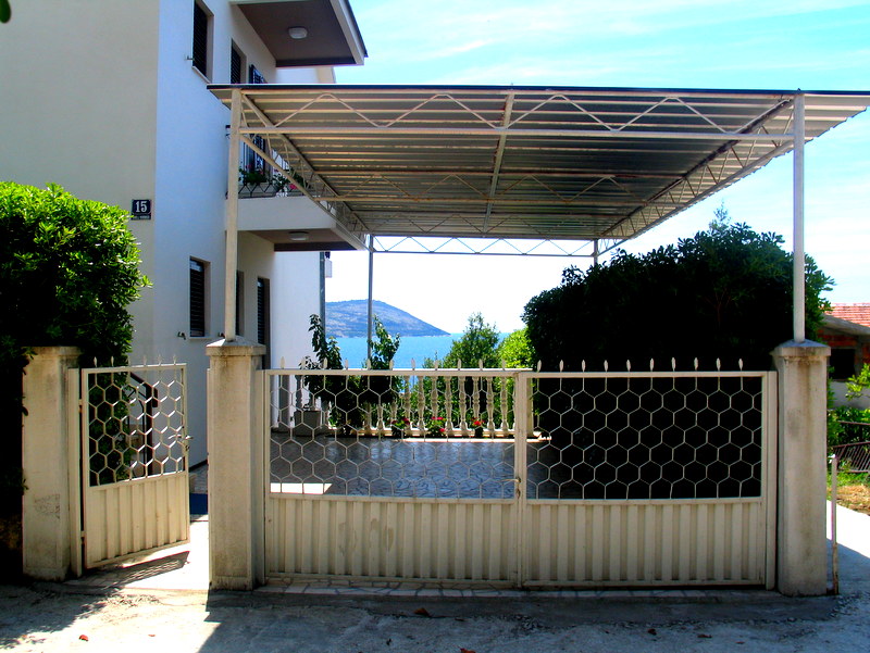 Private house with a parking canopy and sea view in Herceg Novi, Montenegro: facade, gate, and yard area.