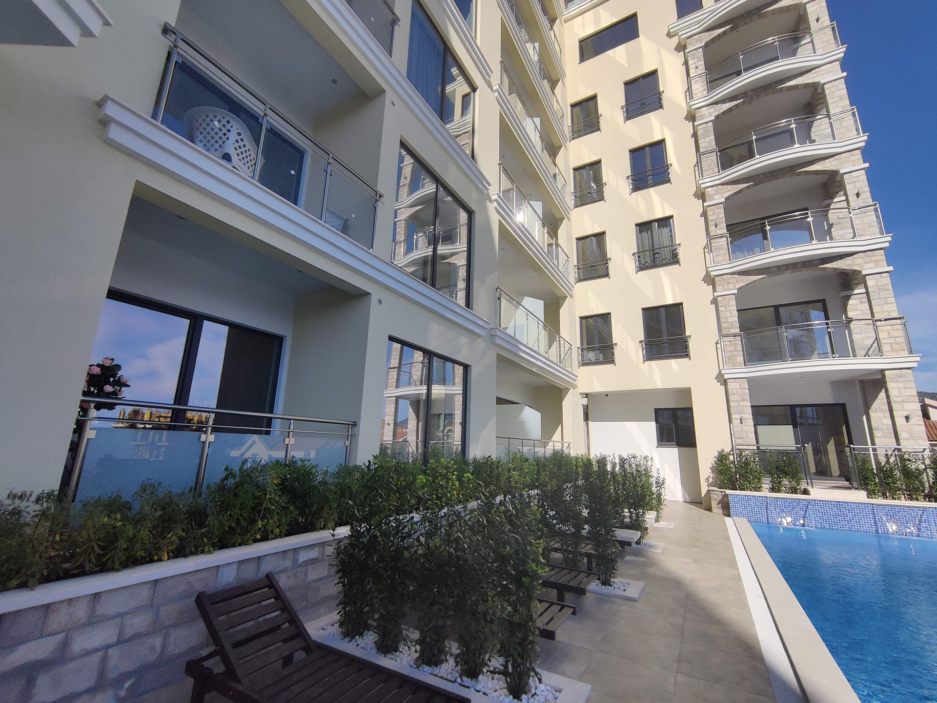 Modern MonteDreams residential complex in Bečići, Montenegro: pool, sun loungers, and apartment terraces with panoramic windows