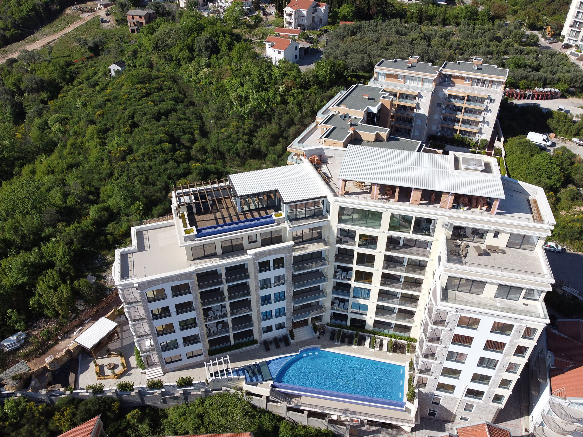 Aerial view of the MonteDreams residential complex in Bečići, Montenegro: a modern building with a pool and terraces.