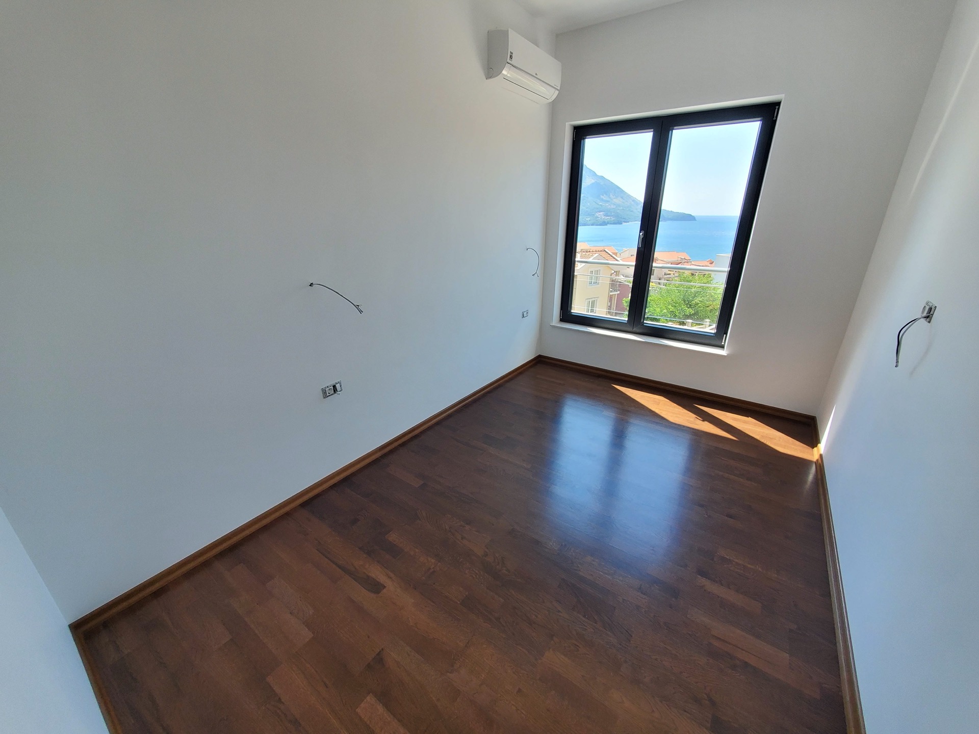 Bright bedroom in MonteDreams residential complex, Becici, Montenegro: parquet floor, air conditioner, and panoramic sea view.
