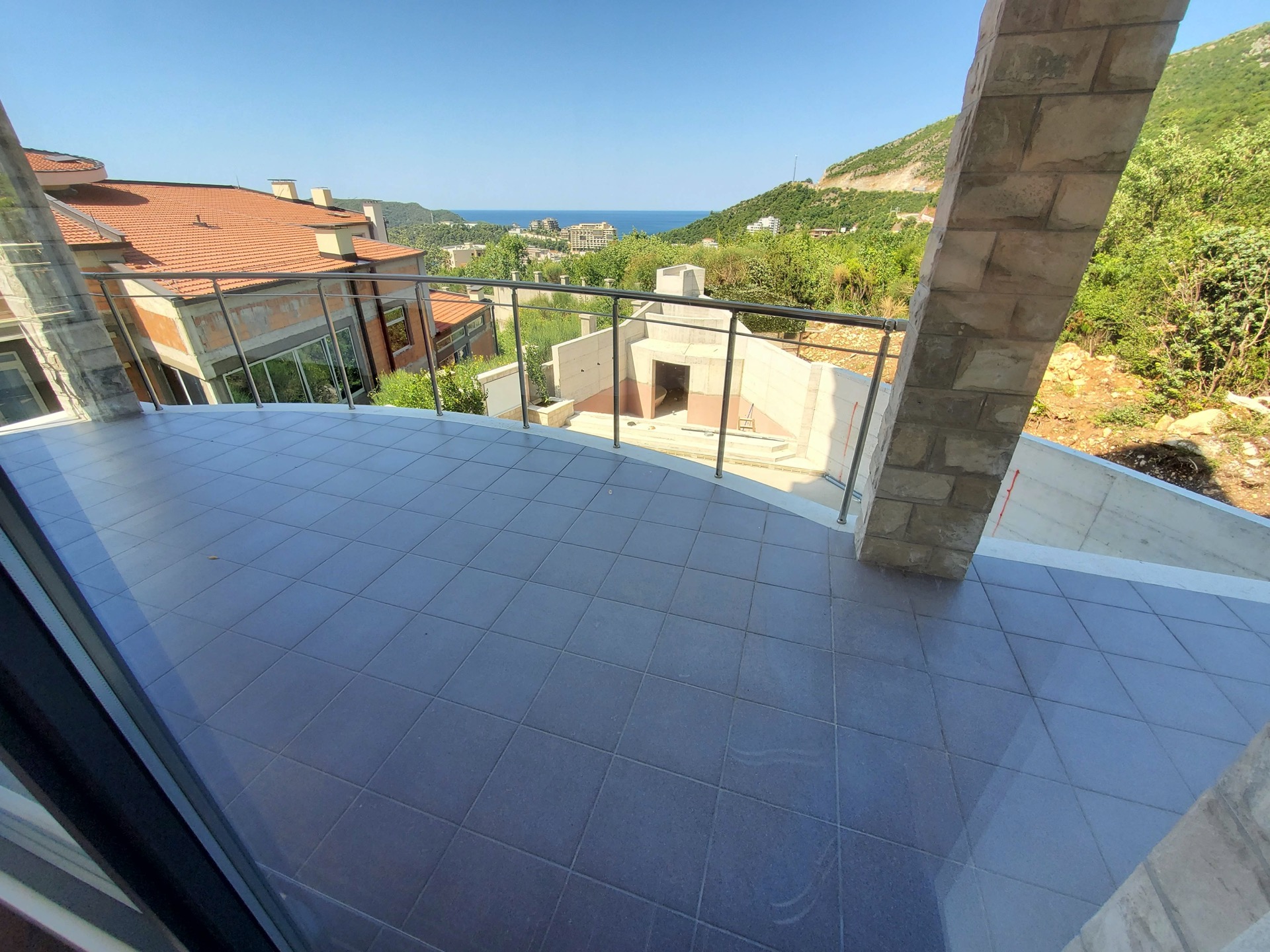 View from the terrace of the MonteDreams complex in Becici, Montenegro: tiled floor, panoramic view of the sea and mountains.