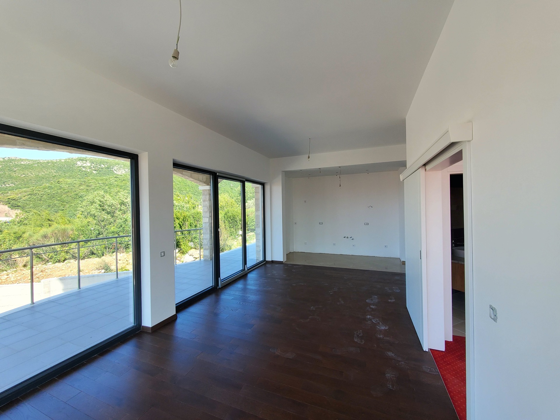 Living room with panoramic windows and a terrace in the MonteDreams residential complex, Bečići, Montenegro. Light finishes and dark parquet flooring.