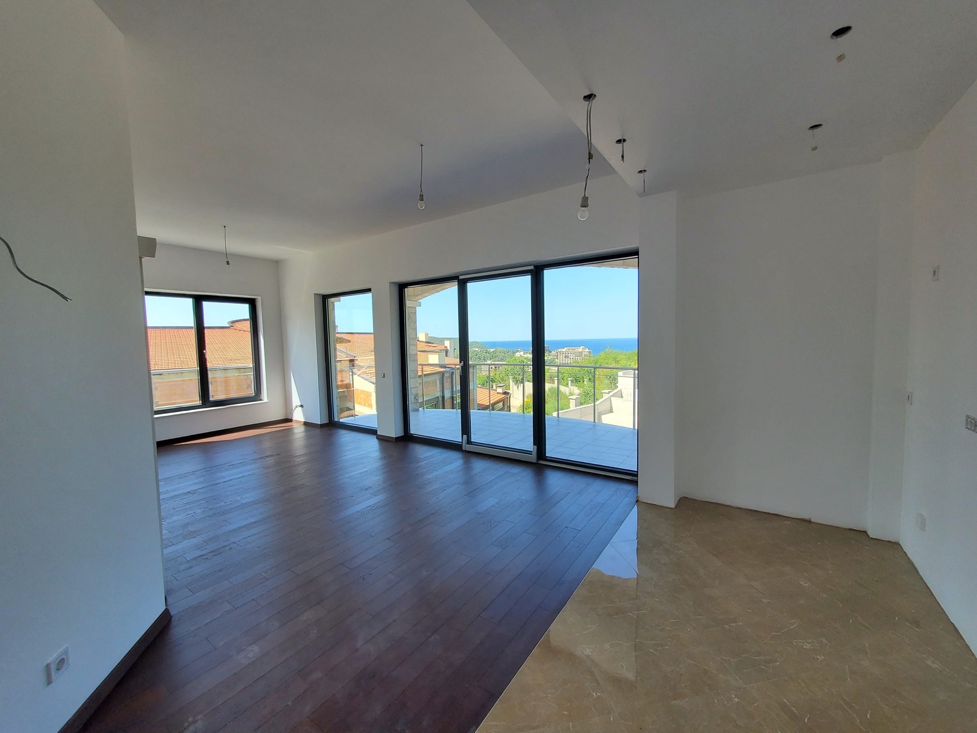 Living room in MonteDreams residential complex, Bečići, Montenegro: panoramic windows, sea view, combined wood and stone flooring.