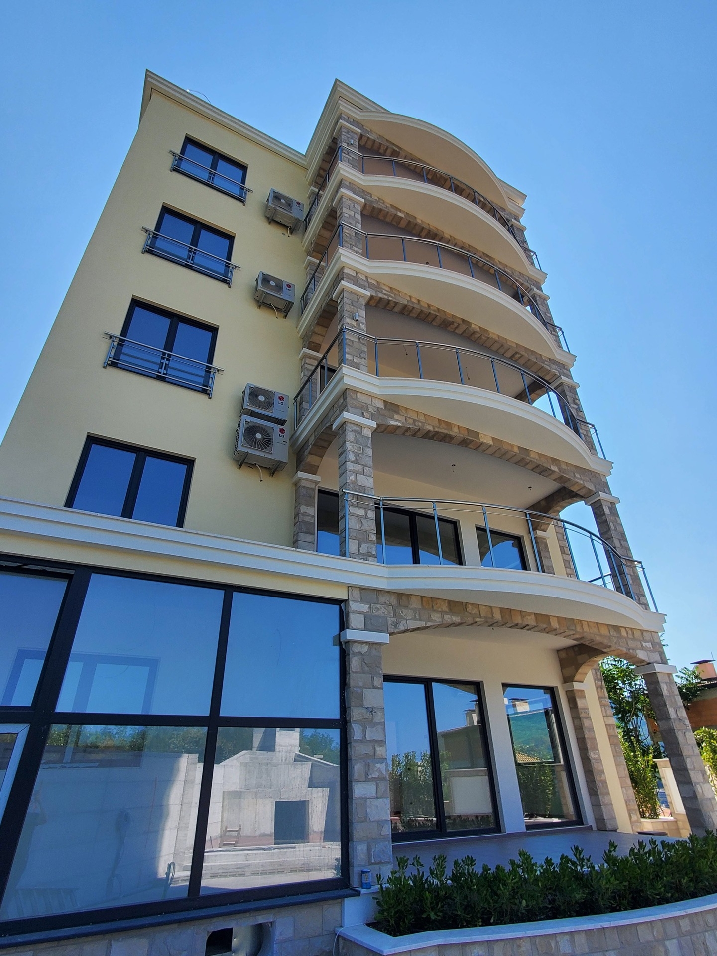 Facade of the MonteDreams residential complex in Bečići, Montenegro: a modern building with stone cladding and panoramic windows.