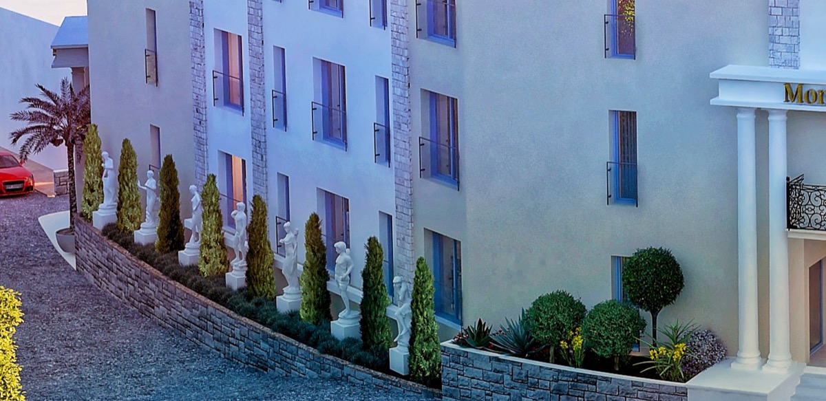 Facade of the MonteDreams residential complex in Bečići, Montenegro: a modern building with columns, statues, and landscaped design.