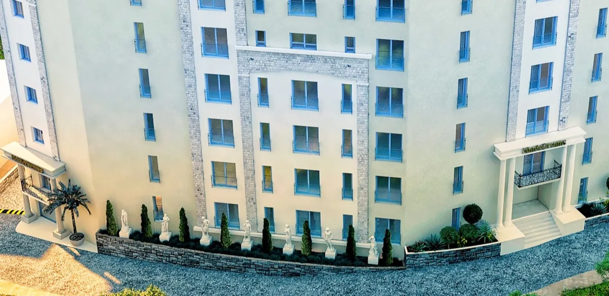 View of a multi-story building facade with balconies, columns, and decorative statues along a low wall.