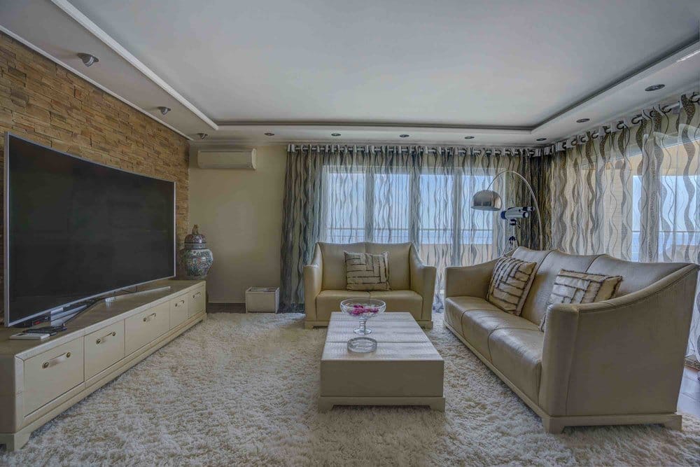 Living room in a villa in Sutomore, Montenegro: leather furniture, stone finishes, panoramic windows with sea views.