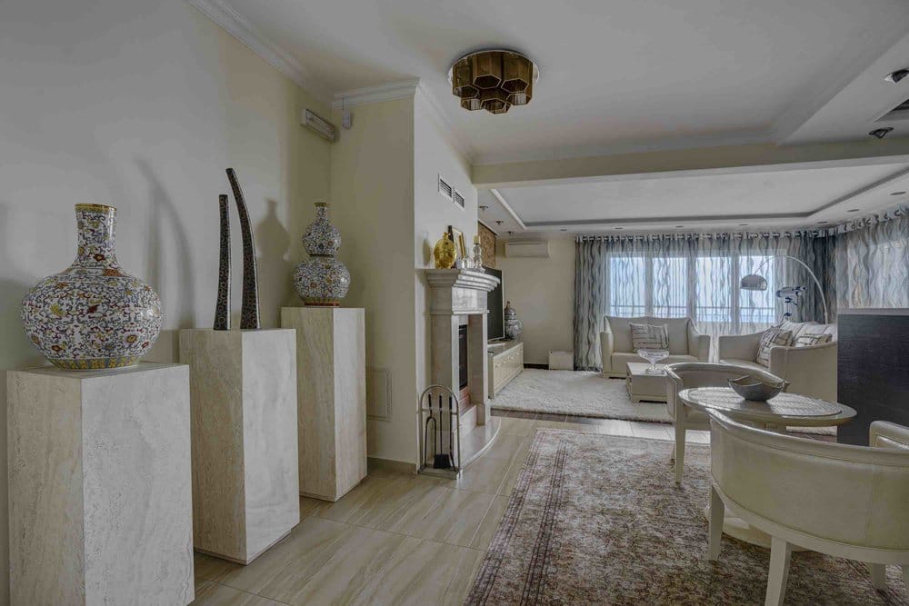 Spacious living room with a fireplace and light-colored furniture in a villa in Seoce, Montenegro: stylish interior with decor and a panoramic view.