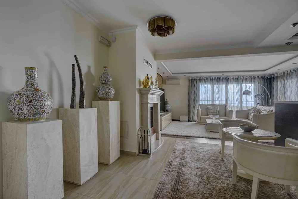 Living room with sofas, rug, fireplace, and decorative vases on pedestals.
