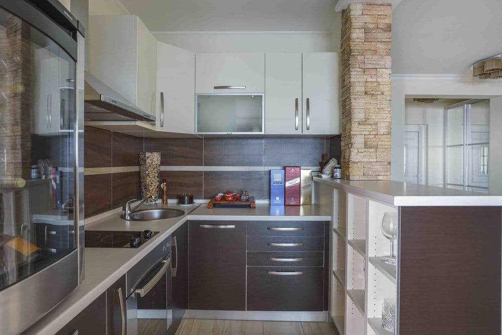 Modern kitchen with a bar counter and stone finishes in a villa in Sutomore, Montenegro. Interior with white and dark furniture.