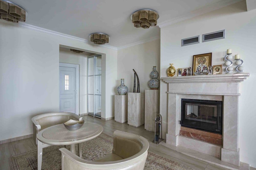 Living room with a marble fireplace and armchairs in a villa in Seoce, Montenegro: stylish interior with decor.