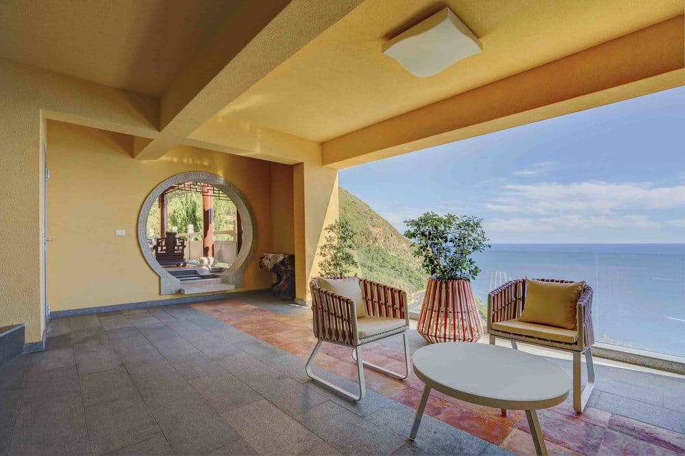 Spacious villa terrace in Seoce, Montenegro: wicker furniture, sea view, and a decorative round opening in the wall.