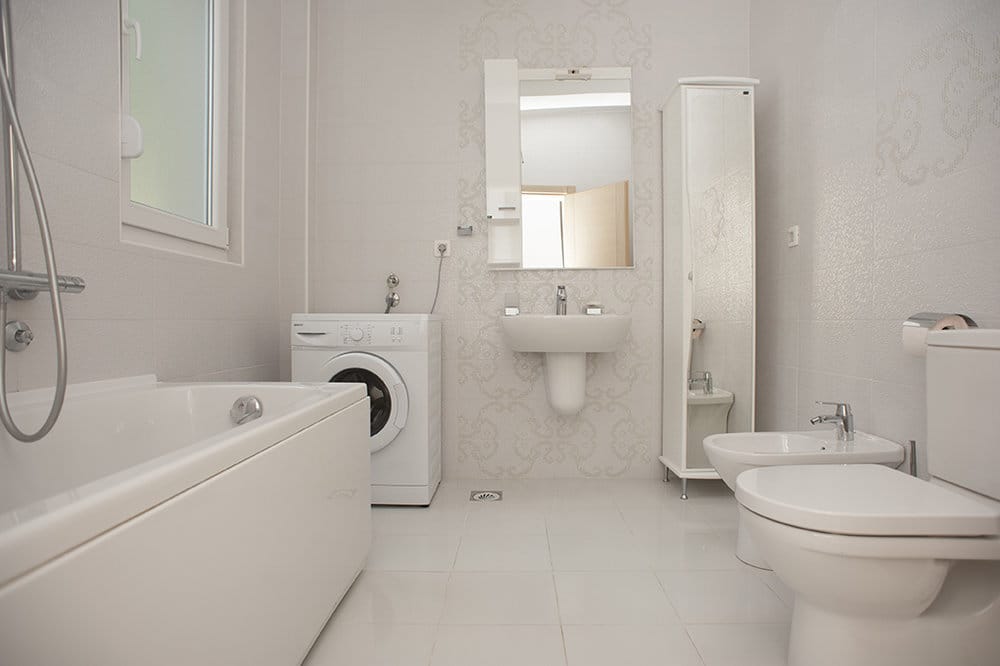 Bright bathroom with a bathtub, washing machine, and bidet in a villa in Perazića Do, Montenegro.
