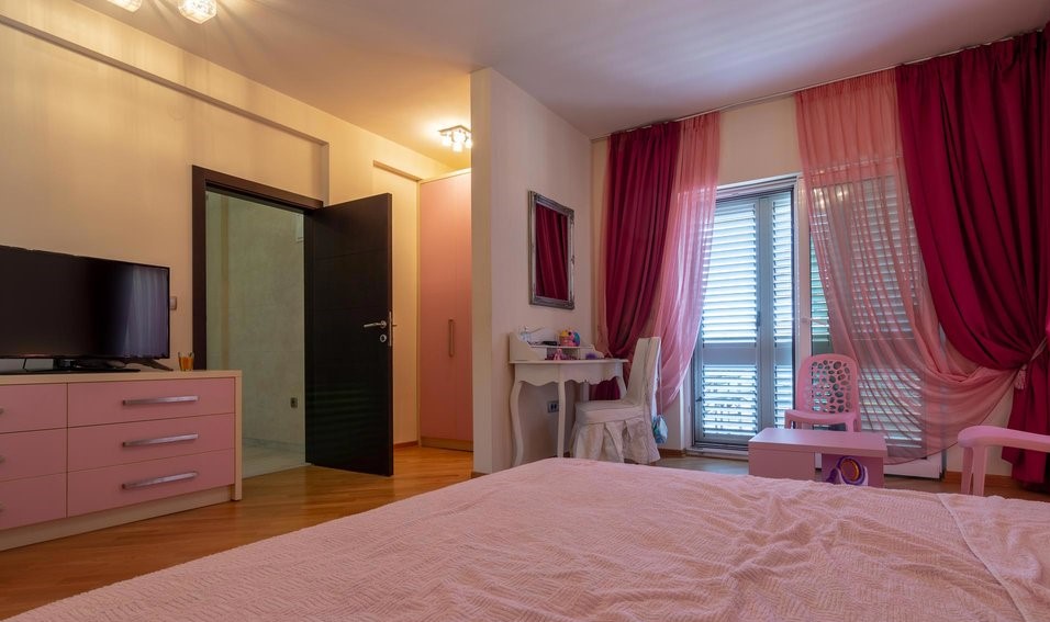 Pink-toned bedroom in a villa in Tivat, Montenegro: double bed, vanity table, and access to the balcony.
