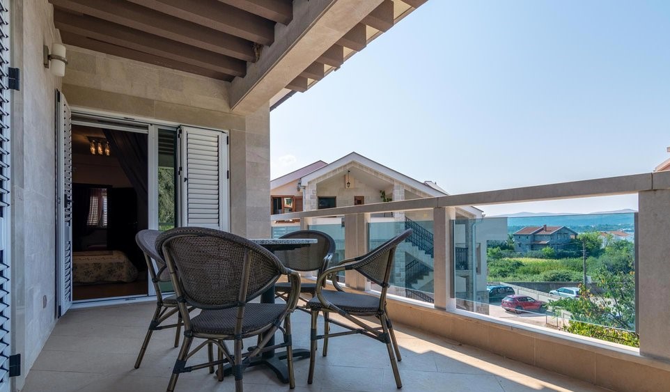 Villa terrace in Tivat, Montenegro: wicker furniture, stone finishes, and panoramic views of the surroundings and the sea.
