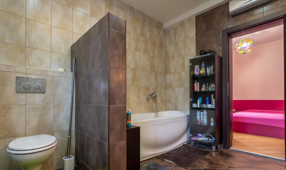 Modern bathroom with a white bathtub and tiled finishes in a villa in Tivat, Montenegro, view of the bedroom.